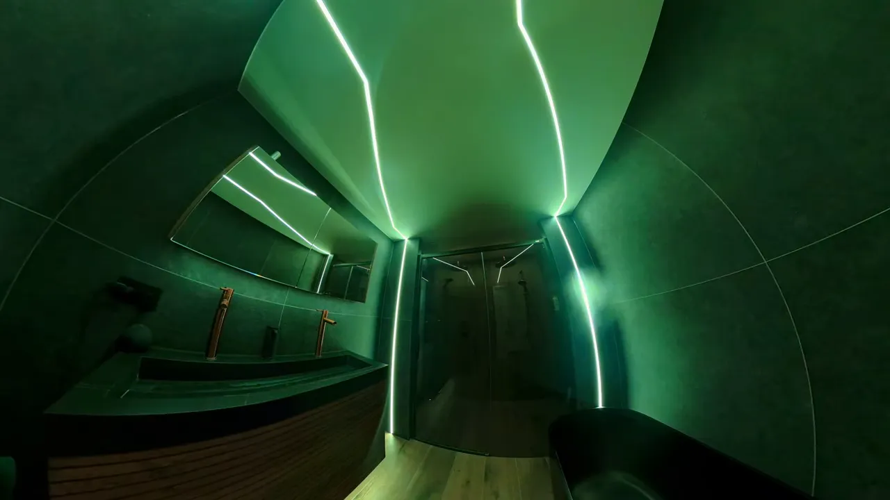 Badezimmer mit geschwungenen Lichtlinien an Decke und Wänden in blauem Licht