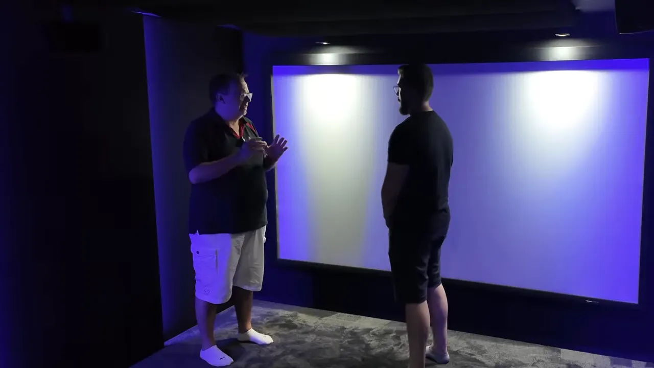 Dunkles Heimkino mit weißer Leinwand, schwarzen Wänden und blauer indirekter Beleuchtung